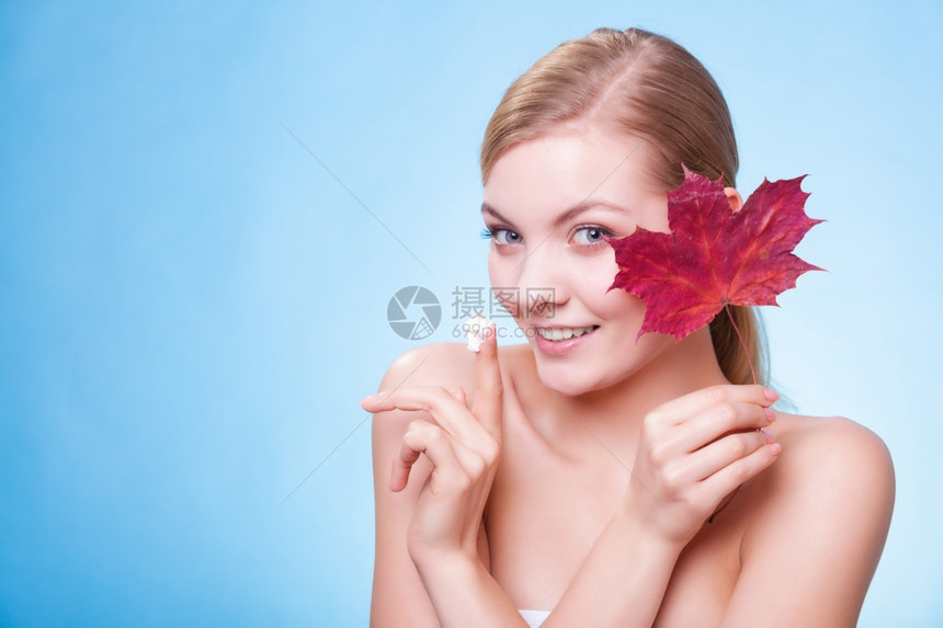 皮肤习惯年轻女表情叶子是蓝色红毛皮的象征女孩用湿润奶油照顾干燥的皮肤美容治疗图片