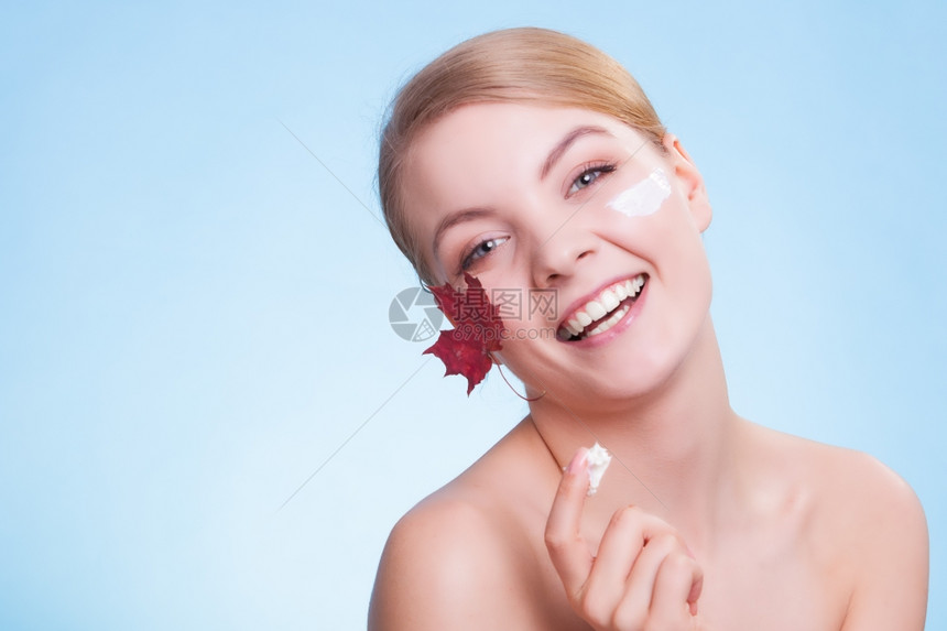 皮肤习惯年轻女表情叶子是蓝色红毛皮的象征女孩用湿润奶油照顾干燥的皮肤美容治疗图片
