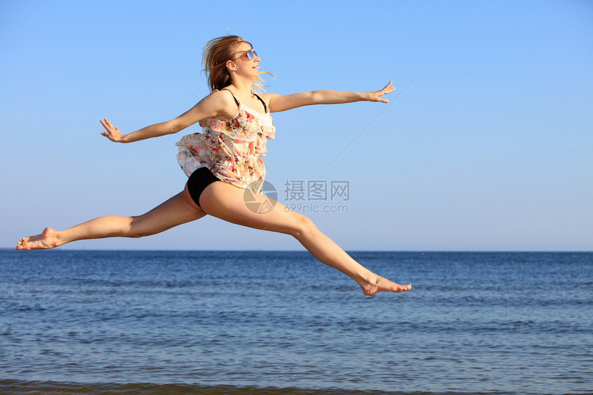 穿暑期服装的年轻女子在海滩上跳跃自由假期暑娱乐概念图片