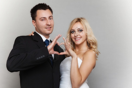 结婚日金发新娘和郎欢喜的金发娘和郎露出双手灰色背景的心形标志图片