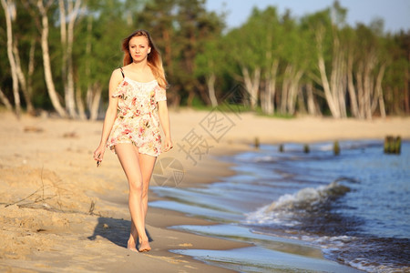 穿暑期服装的年轻女子在沙滩上散步度假暑概念背景图片