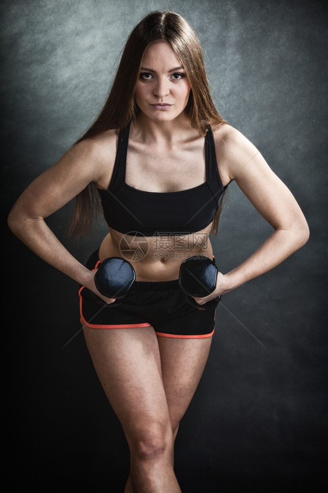 身体健康的女孩身体健康的女人抬起哑铃的重量用锻炼运动用哑铃训练肩部肌肉灰色背景图片