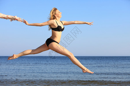 在海滩上跳快乐的姑娘在比基尼适合运动健康的感身体女人享受风自由假期暑图片