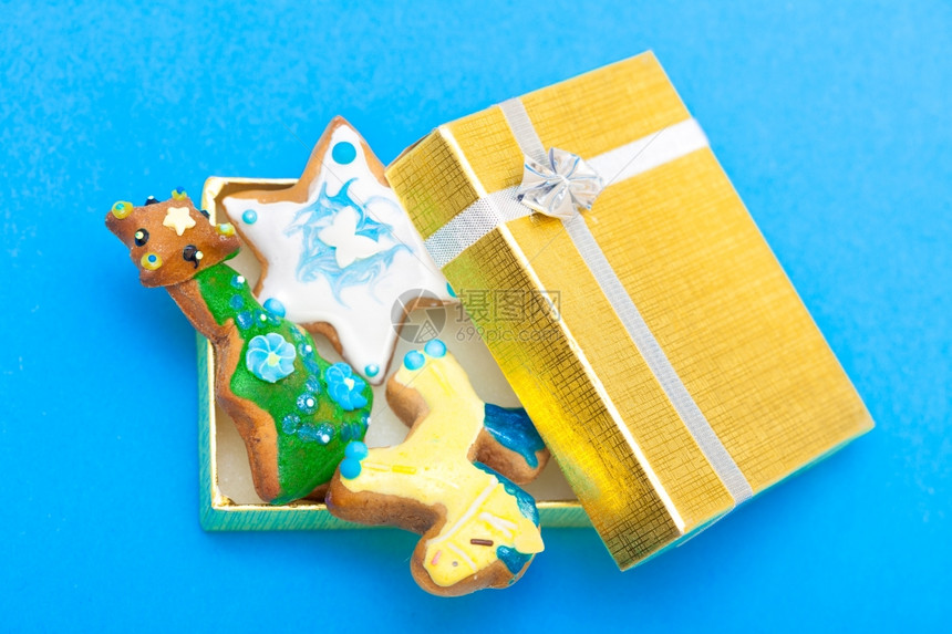 圣诞手工做的姜饼蛋糕有冰淇淋和装饰甜点在金礼物盒里蓝底带银丝假日概念图片