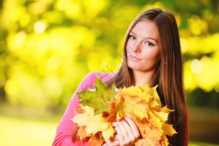 秋天季节快乐的年轻女孩肖像在秋天公园森林里有很多彩的叶子图片