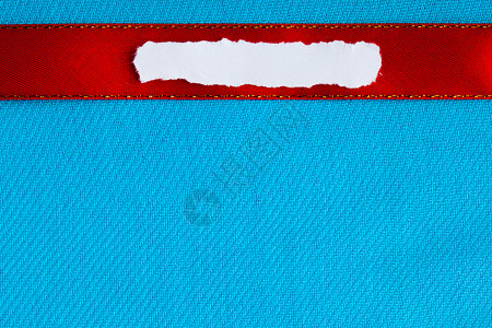 一块白撕或碎的纸条横幅空白的复制间用于在蓝布背景上的文字信息红丝带背景图片