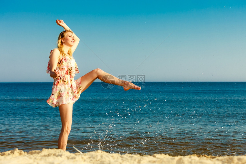 暑假穿期服的姑娘在海岸上泼水年轻女人在海上放松愉快夏天图片