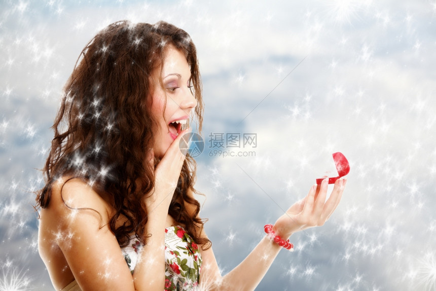 令人惊讶的快乐女孩年轻打开红心的礼物盒与订婚戒指情人节冬季雪幕背景图片