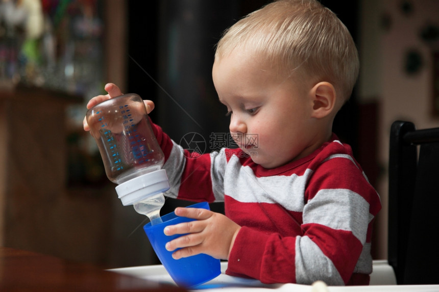 婴儿男孩玩瓶装和杯子在室内饮酒图片