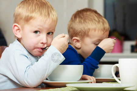 两位金发兄弟男孩在桌边吃玉米片早餐图片