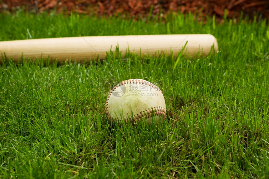 在天然草地上的木棍面前旧棒球的近距离水平相片图片