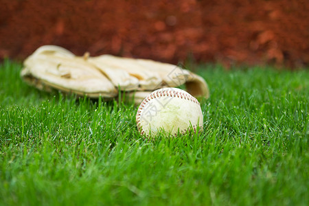 内野在自然草场背景上戴手套的旧棒球横向近照背景