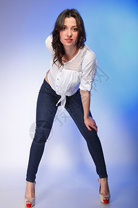 穿着时装牛仔裤穿着蓝底高跟鞋的时尚年轻又大的女人肖像图片