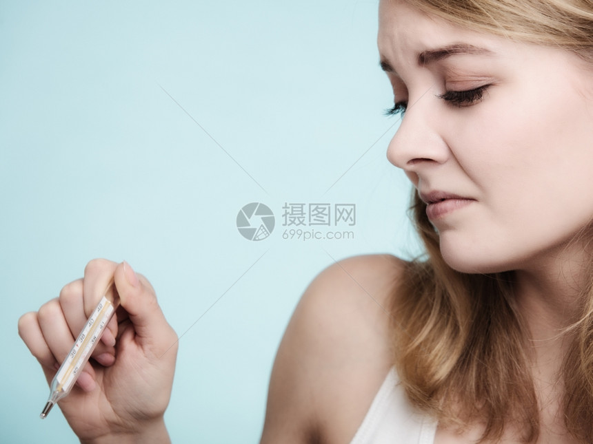 高温的女人发烧病检查蓝色的汞温度计图片