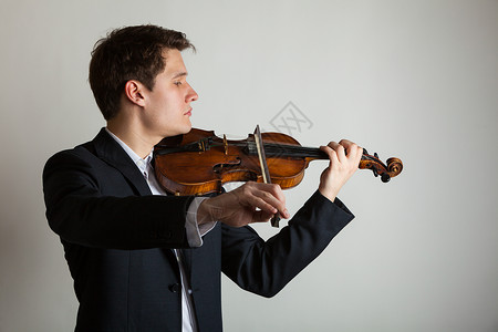 斯特拉迪瓦利乌斯年轻优雅的小提琴家手在灰色上拉小提琴古典音乐演播室拍摄背景