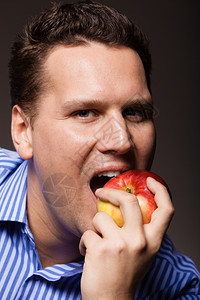快乐的年轻人在黑暗灰色上吃着咬苹果季节水建议健康营养或牙科护理图片