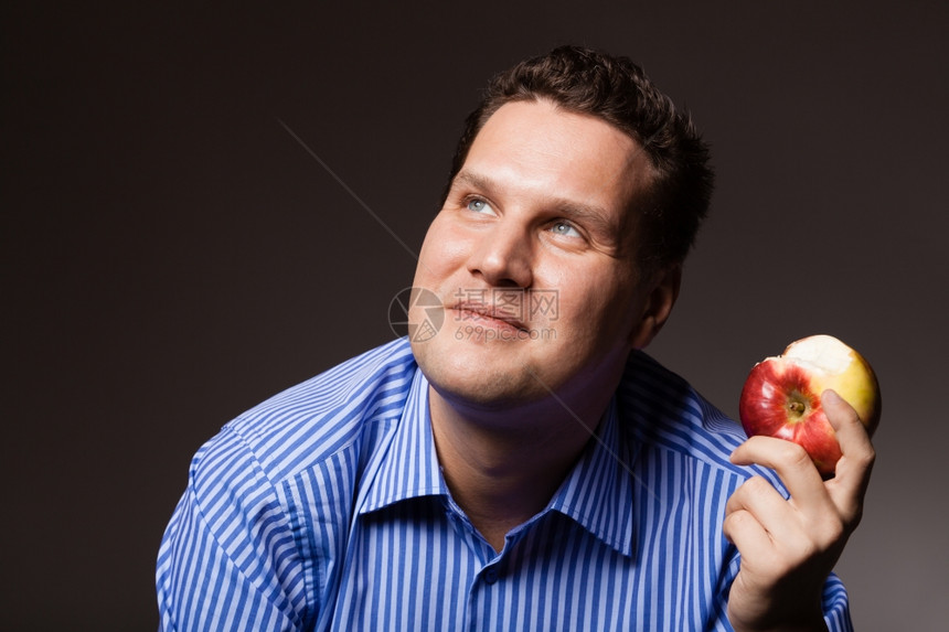 快乐的年轻人在黑暗灰色上吃苹果季节水有人建议健康营养图片