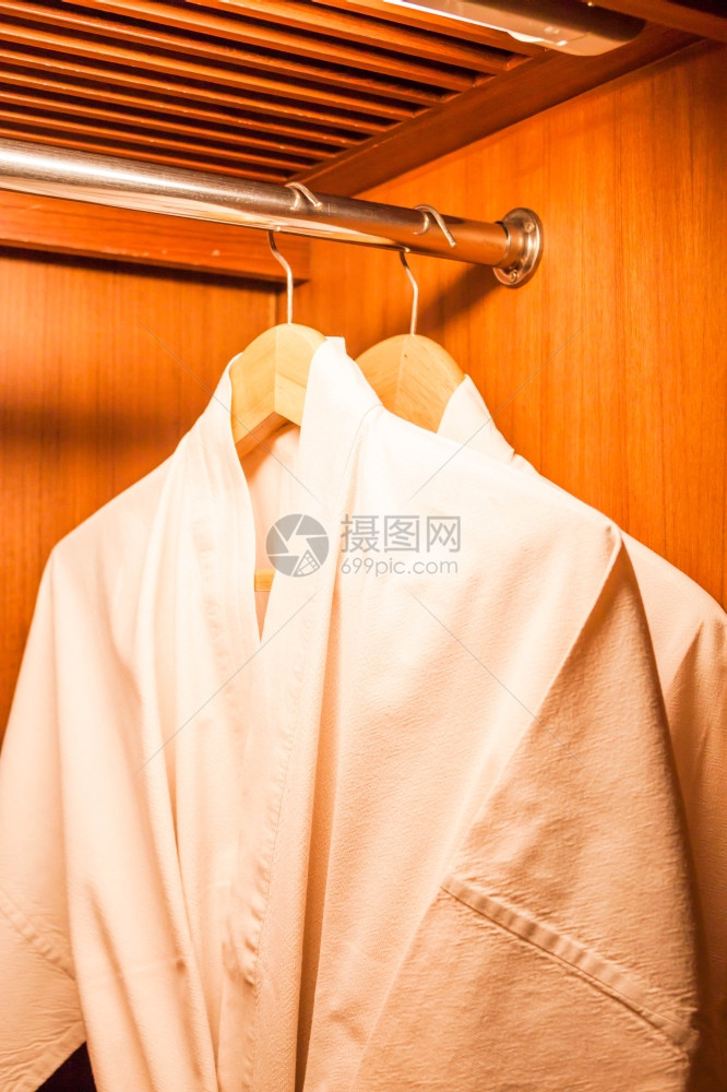 在旅馆衣柜内挂有木衣架的白袍图片