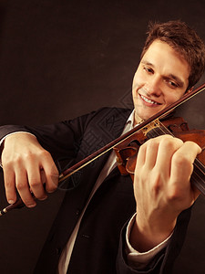 年轻优雅的小提琴家手玩黑色小提琴古典音乐演播室拍摄图片