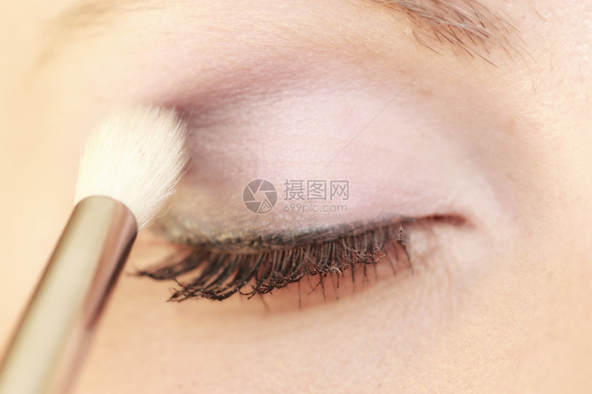 女人用刷子在眼睛上化妆图片