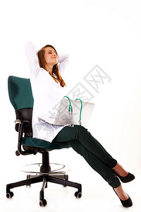 从事笔记本电脑工作的女医生在白种背景的情况下在工作场所伸展图片