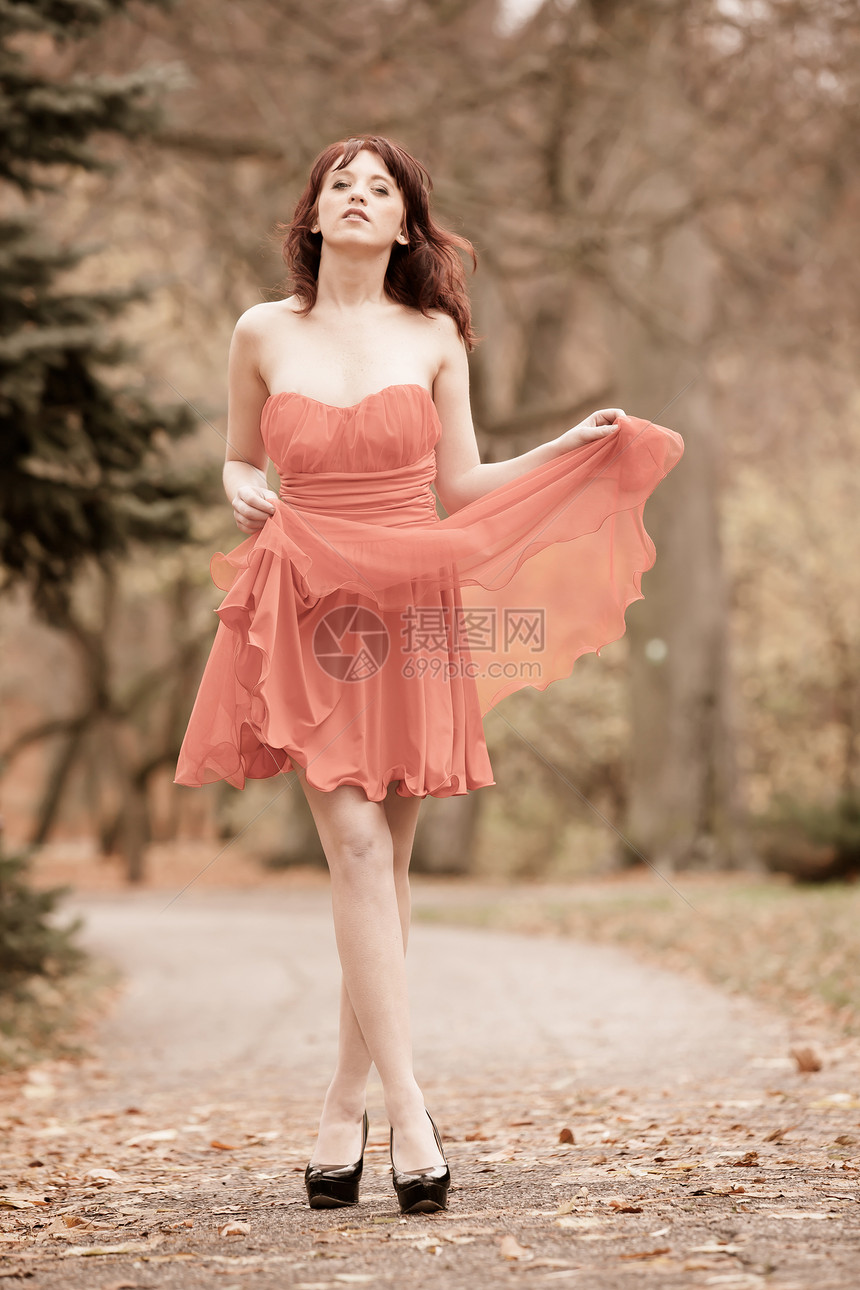 穿着红裙子的全长时装女青年户外放松以公园古老的照片Sepia语调行走图片