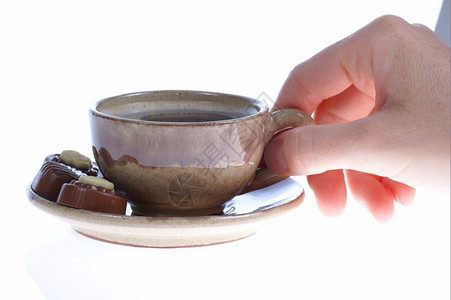一杯热饮料喝咖啡或茶和人手的巧克力图片