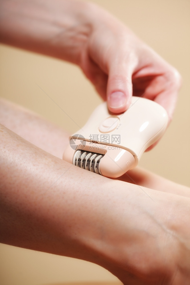 妇女用电剃须刀腿在橙子上刮落美容和皮肤护理概念图片