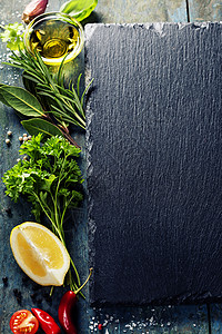 食物背景包括草药香料橄榄油盐柠檬和蔬菜石板木料背景图片