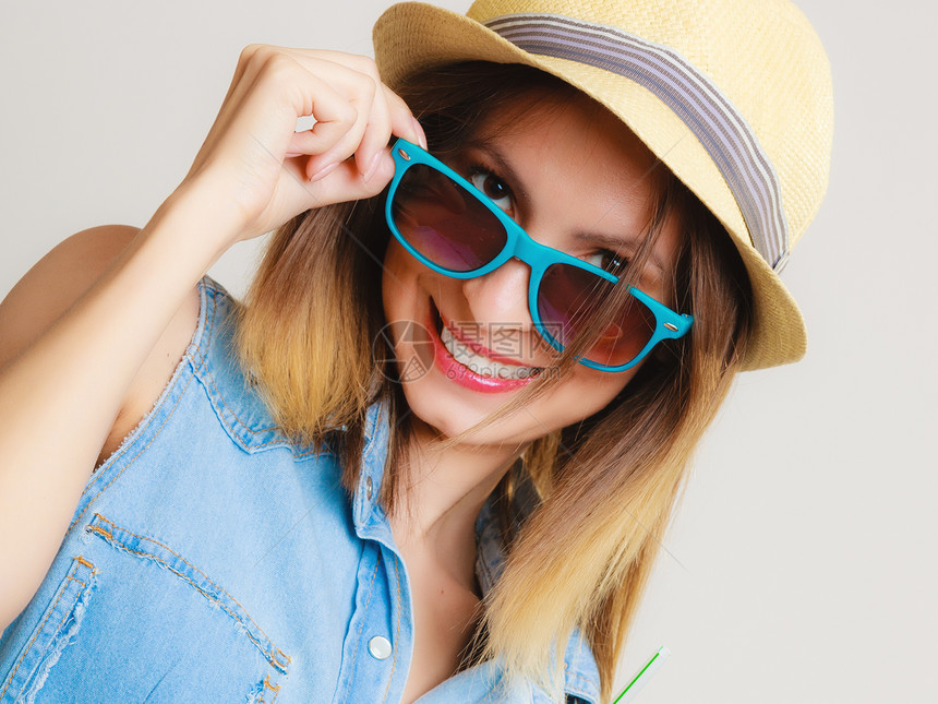 夏衣蓝太阳镜和草帽的快乐女孩灰色的微笑女游客肖像图片