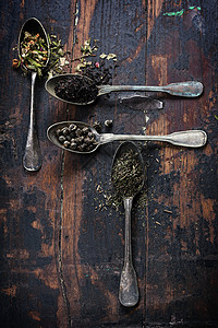 木制背景的各种茶叶黑色绿和草药图片