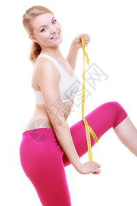 健美的体育女孩微笑子用白色背景隔离的测量磁带大腿的尺寸图片