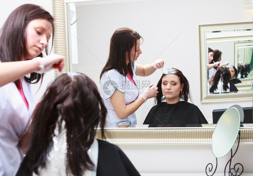 专业女理发师在设计廊对女客户适用彩色妇女染发头色过程图片