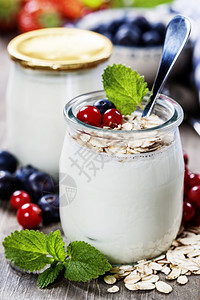 蓝莓背景前加燕麦的酸奶在玻璃罐子里图片
