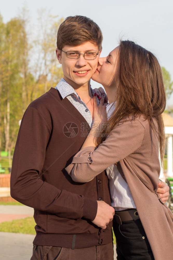 年轻时尚优雅的一对情侣在欧洲城市公园装扮可爱的女孩亲吻一个时髦的男人图片