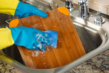 在厨房水槽内用海绵和肥皂水清洗竹切板背景图片