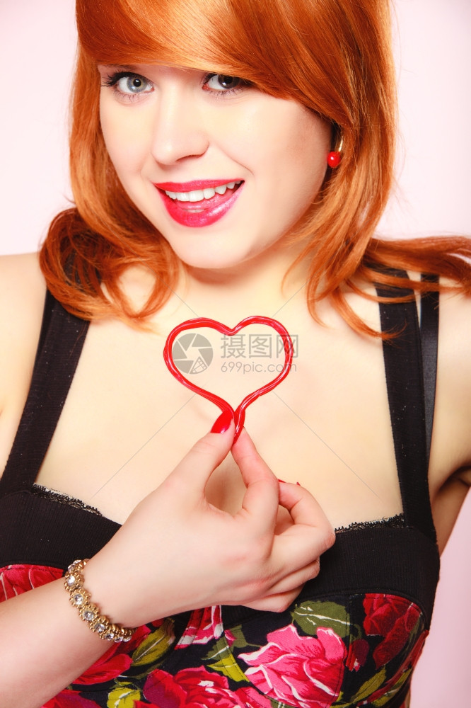 快乐和爱的概念红发女人快乐微笑的女孩胸前抱着情人节的红心图片