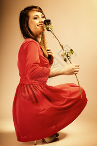 美丽的时装女郎穿着红袍干玫瑰照片以旧色彩图像风格拍摄背景图片