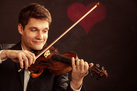 年轻可爱的小提琴家手在黑人背景上演奏小提琴配着情人心爱符号古典音乐工作室拍背景图片