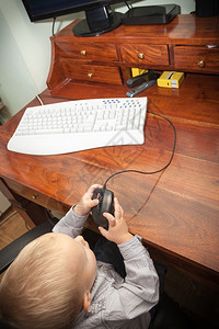 快乐的童年聪明小男孩在家里的台式电脑上玩耍技术图片