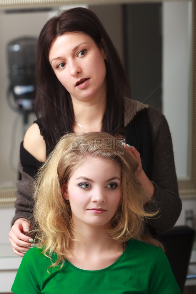 美丽的笑脸女孩有金发卷由理师负责梳女客户年轻子在美发容院型风格图片
