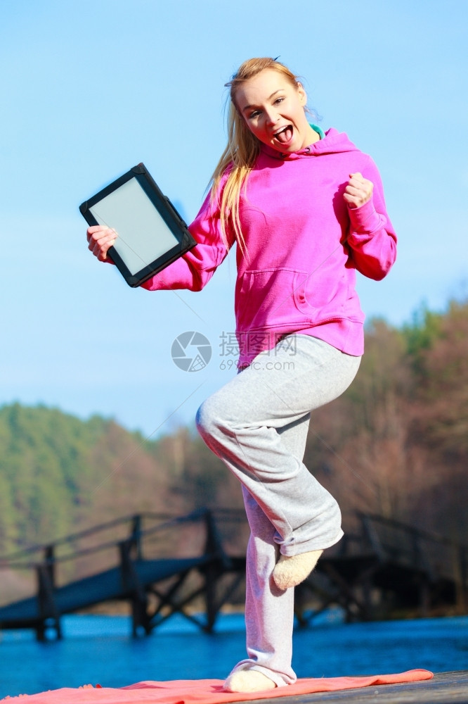 全身体健壮的女运动员穿着粉红色运动服的少女在户外用平板触摸电脑空白的格屏幕图片