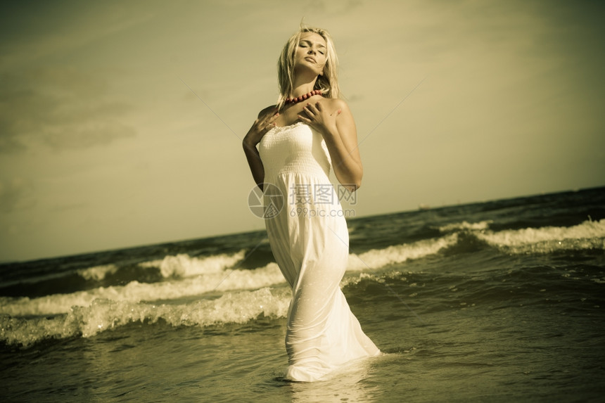 假期旅行和自由概念穿着白裙子的漂亮女孩在海滩上摆姿年轻女在海边放松图片