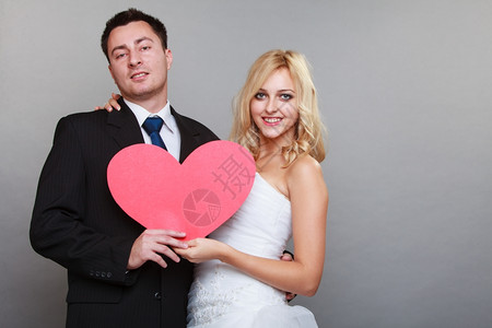 结婚日金发新娘和郎带着红心象征灰色背景的红心新娘和郎快乐图片