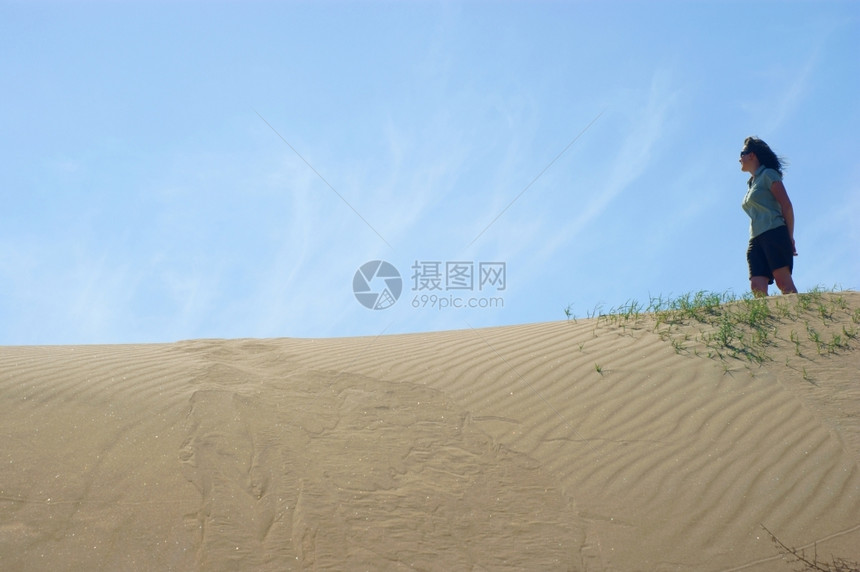 女方在沙丘上蓝的天空图片