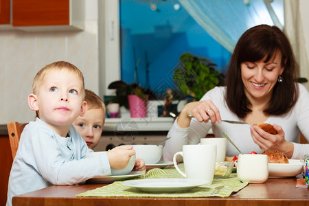 母亲和两个金发兄弟在餐桌上吃早餐图片