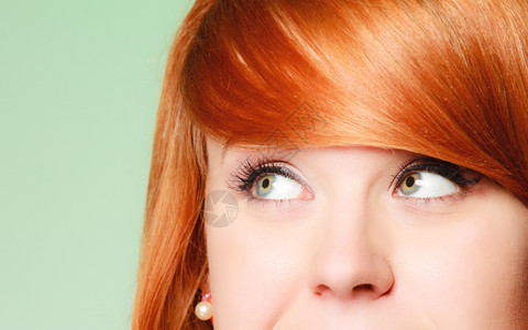 心思深的年轻女红头发孩思考着向上看绿色背景图片