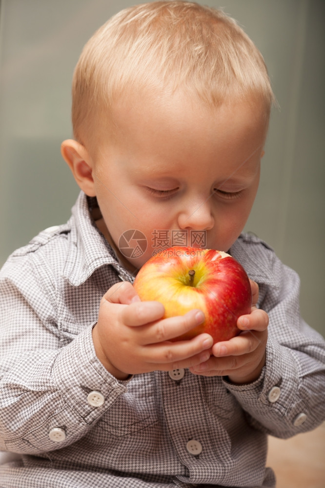 快乐的童年可爱小男孩肖像在家里吃苹果水健康的饮食和营养图片