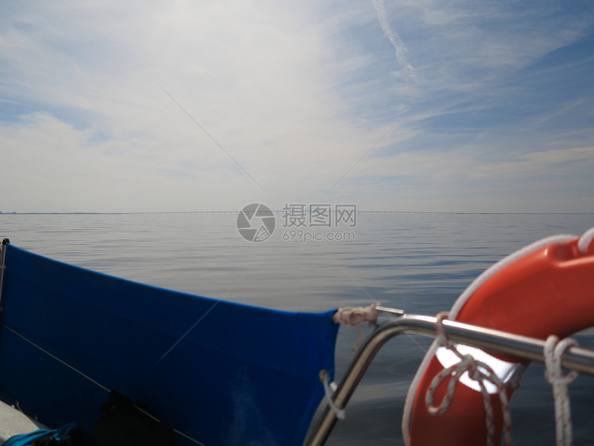 安全饮水支助援圈救护红色生艇员在帆船蓝色天空黄海上的环丹麦和瑞典之间的奥雷松桥是背景图片