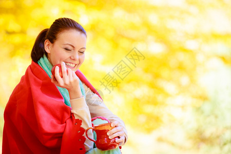 在秋天公园享受热饮咖啡或茶拿着红杯加热饮料黄叶背景图片